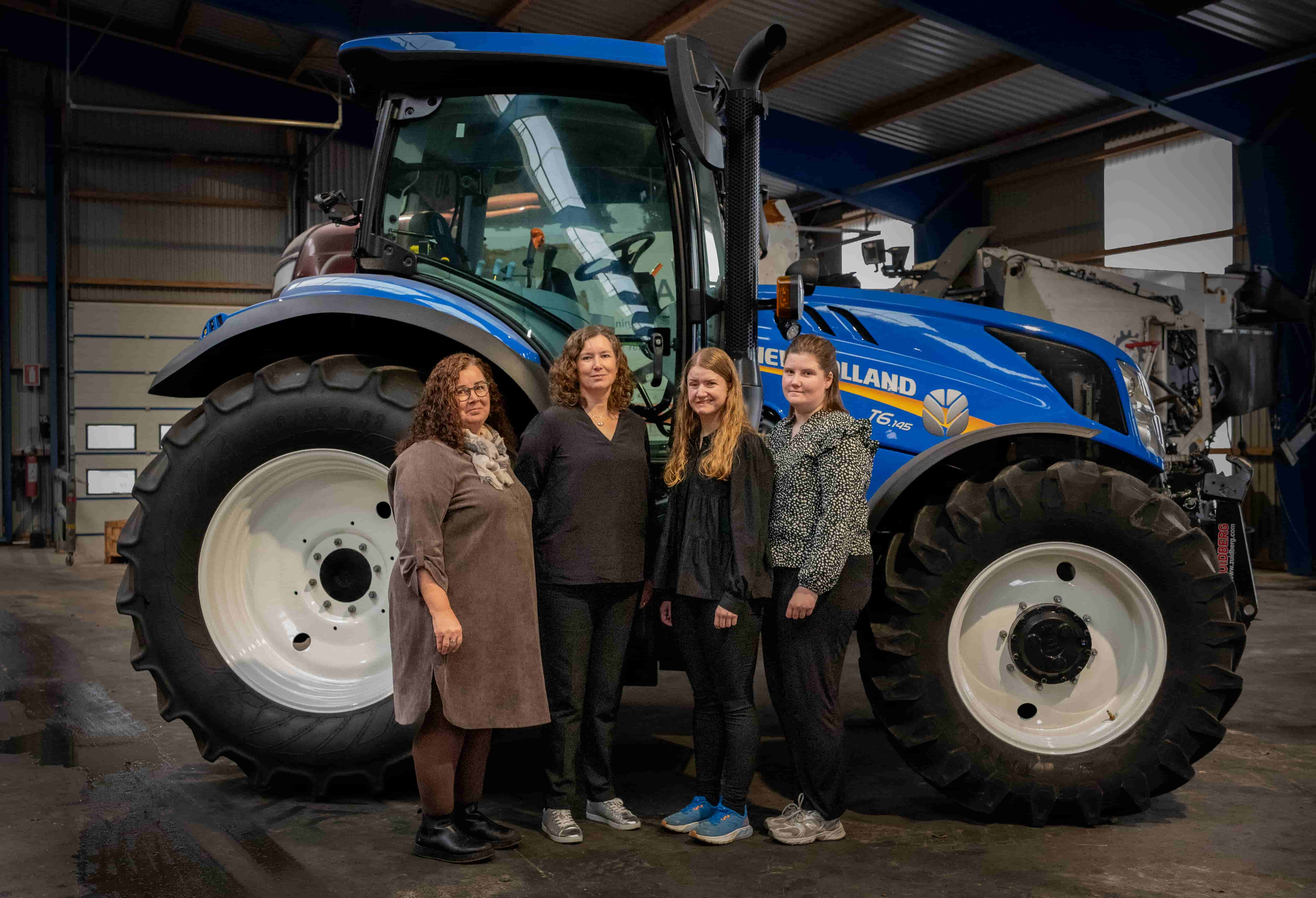 Administrations ansatte står foran en New Holland traktor